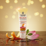 Tube of Sanchomee Lifestyle Mee Glow cream on a wooden surface with flowers and an orange peel.